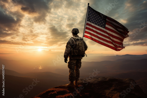 Fototapeta american soldier holding a flag on the peak of a mountain at sunset