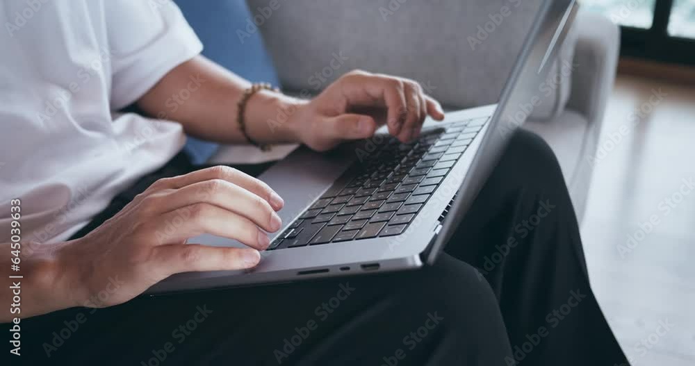 Closeup male student hands typing text on a laptop at on the couch. Close-up student man sitting on sofa at home and studying using laptop computer at home. Distant learning from home. Closeup male student hands typing text on a laptop at on the couch. Close-up student man sitting on sofa at home and studying using laptop computer at home. Distant learning from home.