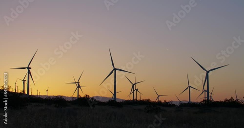 Wind turbines, windmills spinning in a field at sunset