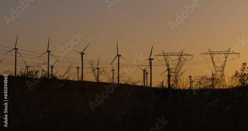 Wind turbines, windmills spinning in a field at sunset