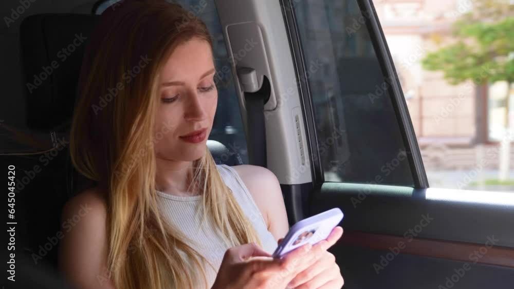 Young woman travelling in a taxi while sitting on back seat of car, typing on the mobile phone. Lifestyle, trip, technology concept. Real time Young woman travelling in a taxi while sitting on back seat of car, typing on the mobile phone. Lifestyle, trip, technology concept. Real time