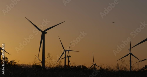 Wind turbines, windmills spinning in a field at sunset
