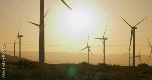 Wind turbines, windmills spinning in a field at sunset