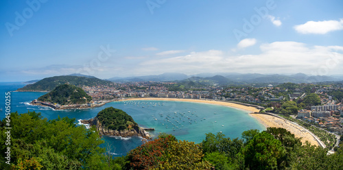 Panoramic view of La Concha beach in the basque city of San Sebastian with sailboats and blue sky. Summer vacation tourist destination seascape.