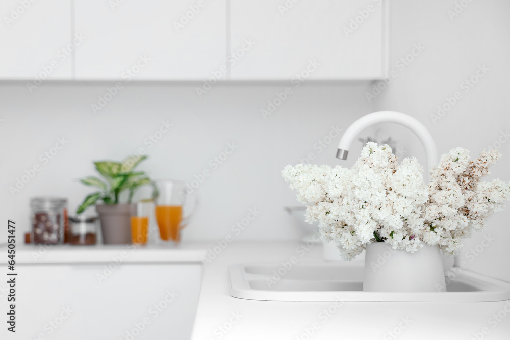 Sink with lilac flowers in light kitchen, closeup Sink with lilac flowers in light kitchen, closeup