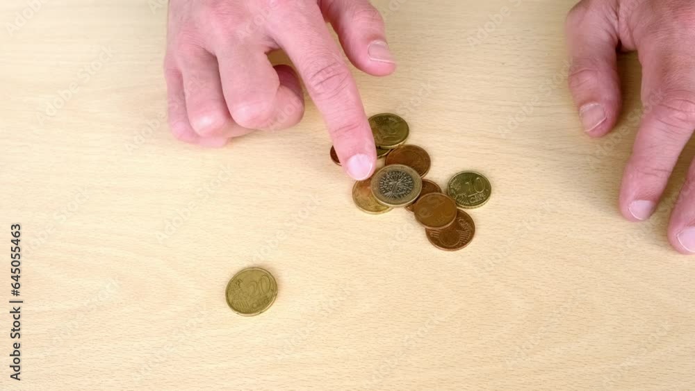 close up male hands lay out, count metal euro coins, manipulates, puts euro union money on wooden table, concept of financial development, human poverty, life insurance, devaluation, inflation, taxes close up male hands lay out, count metal euro coins, manipulates, puts euro union money on wooden table, concept of financial development, human poverty, life insurance, devaluation, inflation, taxes