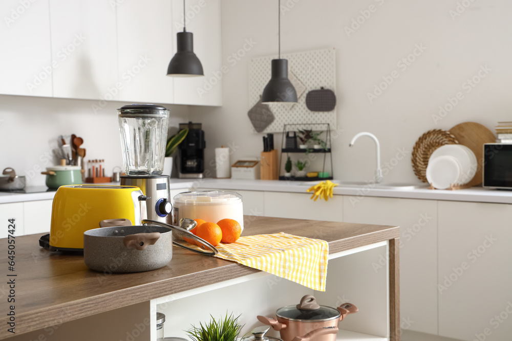 Blender, toaster, juicer, oranges and cooking pot on wooden table in kitchen Blender, toaster, juicer, oranges and cooking pot on wooden table in kitchen