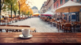 Cup of tea and empty wooden table of outdoor cafe for product display with blurred background. Autumn quiet city street in the background.