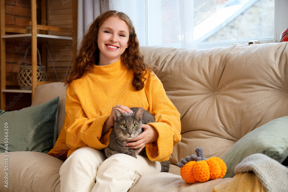 Young woman with cute cat and knitted pumpkin at home