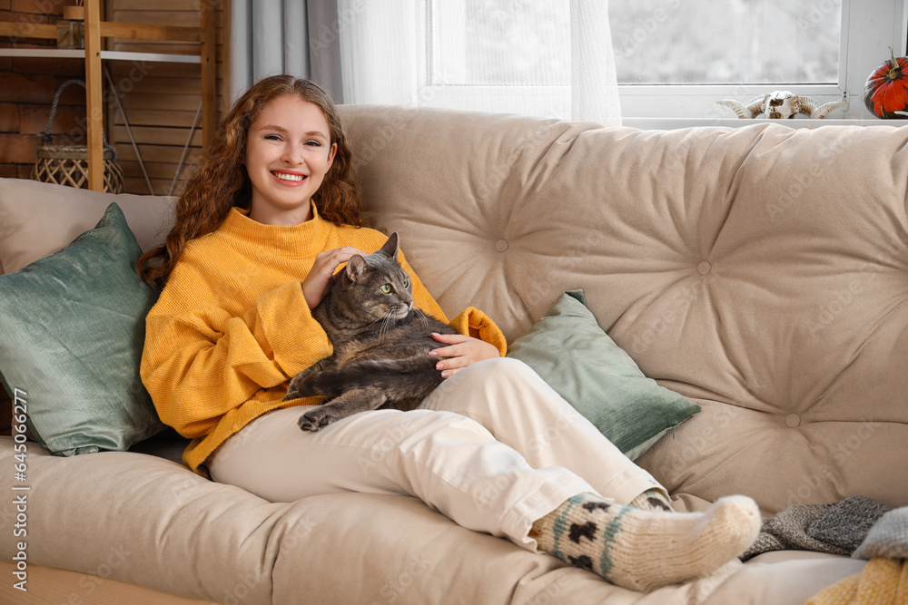 Young woman with cute cat lying on sofa at home