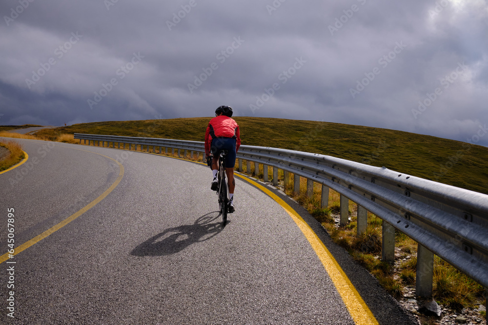 Male cyclist riding a gravel bike in the mountainous terrain on a foggy day.Man cyclist wearing cycling kit and helmet.Motivation image of an athlete.Cyclist enjoying traveling on his bike.Transalpina