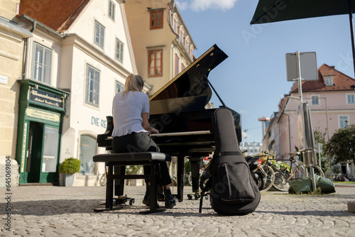 A girl plays the piano on the street of an old European city