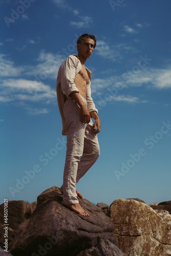 model guy posing on the rocks on the seashore