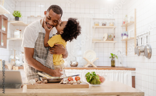 Portrait of little American African black boy parent cooking preparing food with pan in the counter kitchen. Happy  family with father son, father's day, healthcare cooking plant based food concept