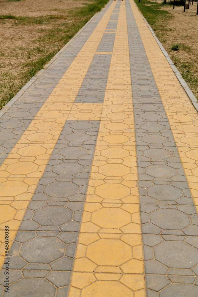 Paved footpath with long slabs of gray and orange.