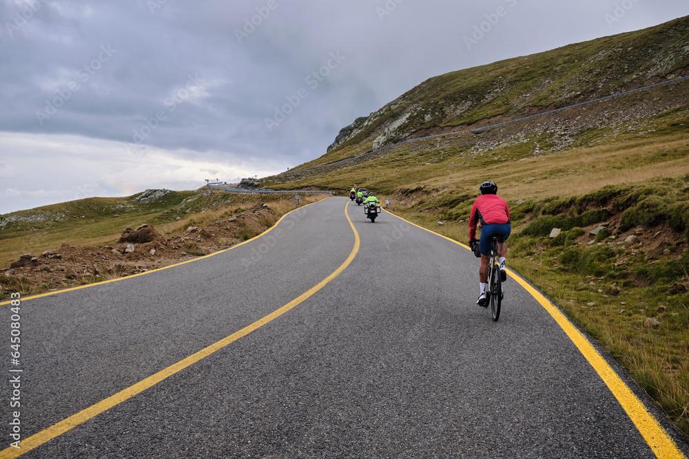 Male cyclist riding a gravel bike in the mountainous terrain on a foggy day.Man cyclist wearing cycling kit and helmet.Motivation image of an athlete.Cyclist enjoying traveling on his bike.Transalpina Male cyclist riding a gravel bike in the mountainous terrain on a foggy day.Man cyclist wearing cycling kit and helmet.Motivation image of an athlete.Cyclist enjoying traveling on his bike.Transalpina