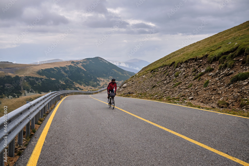 Cyclist is resting.Female cyclist is wearing cycling kit holding energy snack for endurance during bicycle training.Sport nutrition.Sport snack for cyclist.Granola energy bar. Cyclist is resting.Female cyclist is wearing cycling kit holding energy snack for endurance during bicycle training.Sport nutrition.Sport snack for cyclist.Granola energy bar.