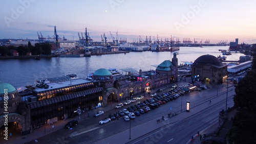 Amazing drone point of view in blue hour on Landungsbrucken (station and as terminal for tourboats). In ditance cranes