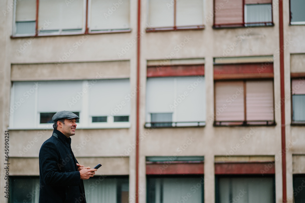 Side view of an executive standing in a city street in rainy weather. Side view of an executive standing in a city street in rainy weather.