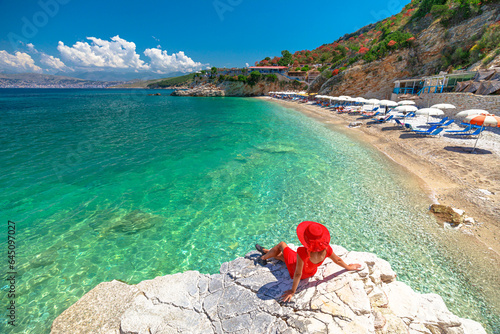 Pulebardha Beach in Albania provides the perfect setting for unwinding, swimming, and immersing yourself in breathtaking surroundings. Woman enjoying beautiful beach view from above a cliff. © bennymarty