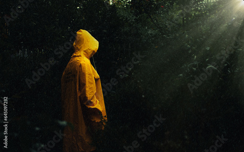 Woman with a yellow jacket in a forest with rain 