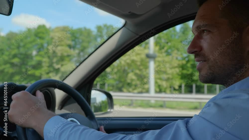 Happy young man holding hands on steering wheel on the right with city view. Side view. Right hand drive car. Lifestyle, travel concept. Real time Happy young man holding hands on steering wheel on the right with city view. Side view. Right hand drive car. Lifestyle, travel concept. Real time