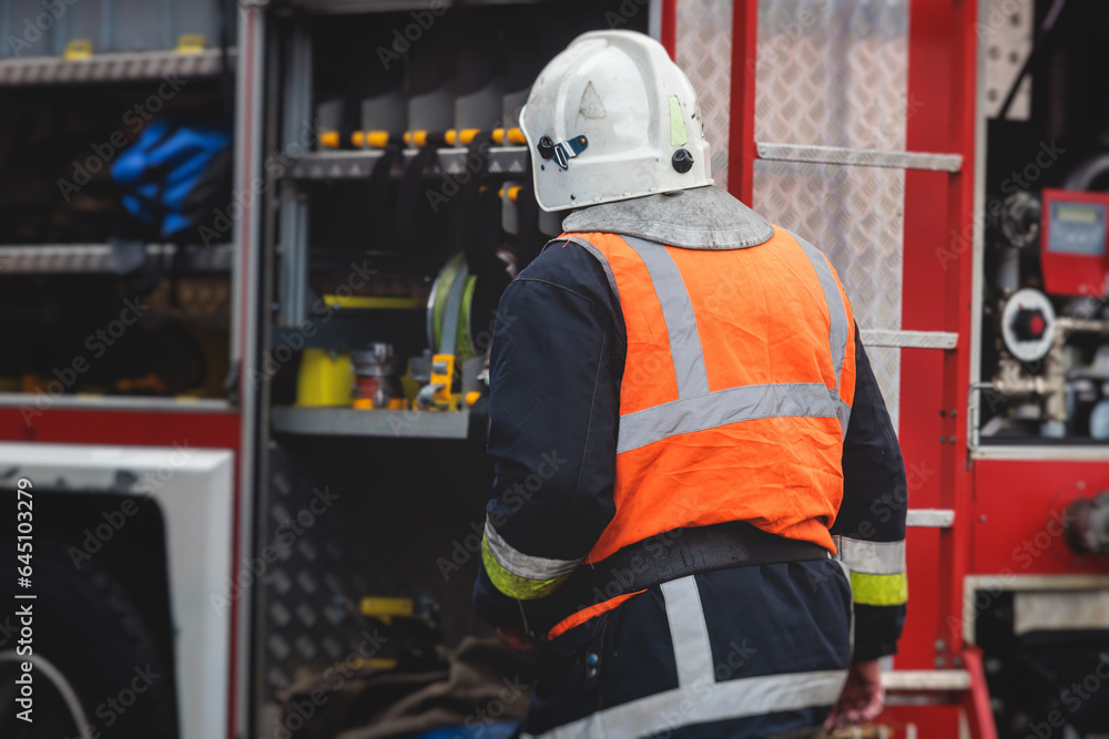 Group of fire men in protective uniform during fire fighting operation in the city streets, firefighters brigade with the fire engine truck vehicle in the background, emergency and rescue service Group of fire men in protective uniform during fire fighting operation in the city streets, firefighters brigade with the fire engine truck vehicle in the background, emergency and rescue service