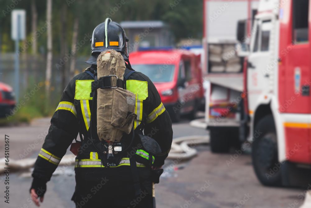 Group of fire men in protective uniform during fire fighting operation in the city streets, firefighters brigade with the fire engine truck vehicle in the background, emergency and rescue service Group of fire men in protective uniform during fire fighting operation in the city streets, firefighters brigade with the fire engine truck vehicle in the background, emergency and rescue service