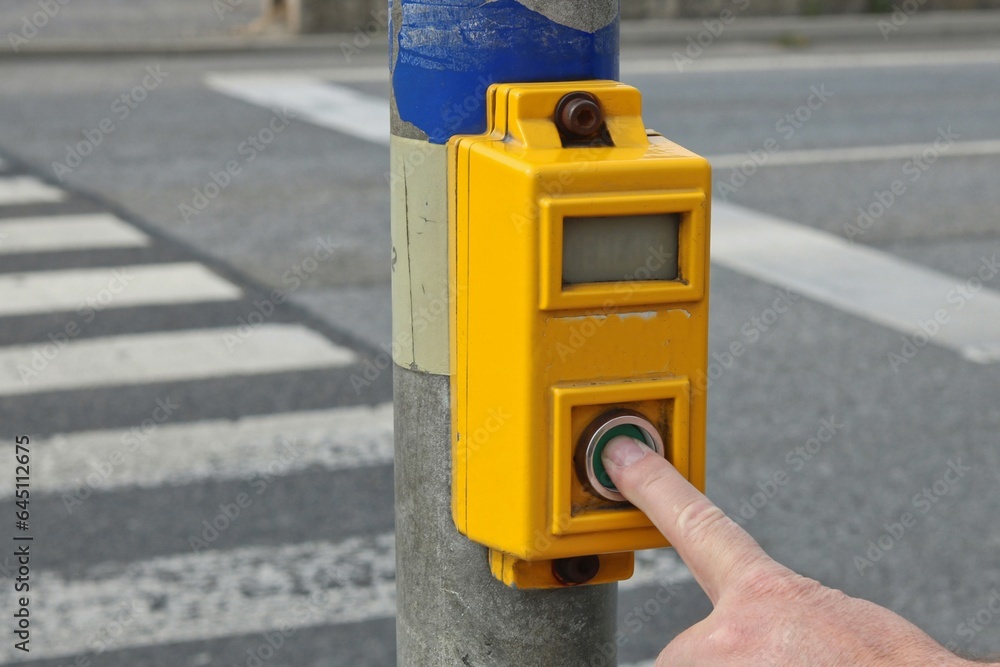 Pedestrian finger pressing a button on a pedestrian crossing