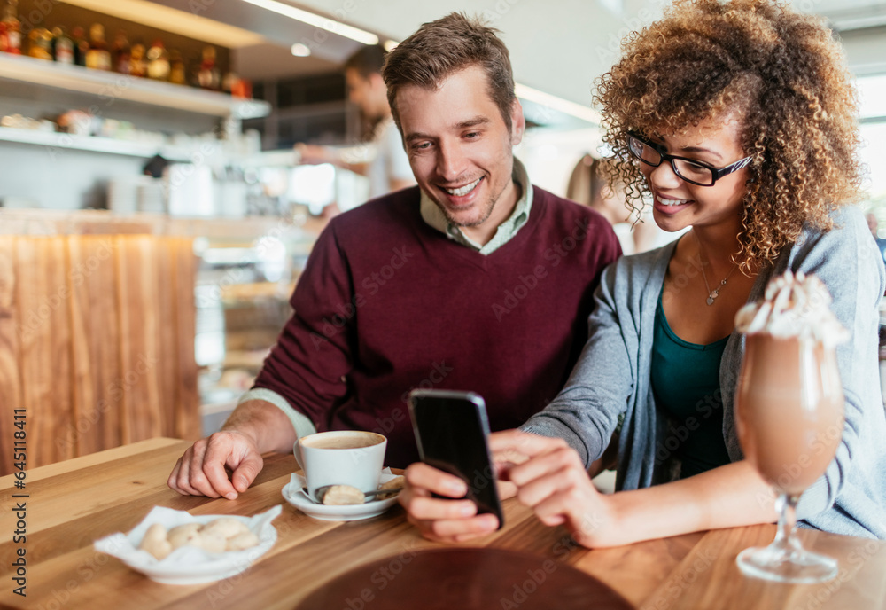 Young mixed couple using a smartphone while on a date in a cafe