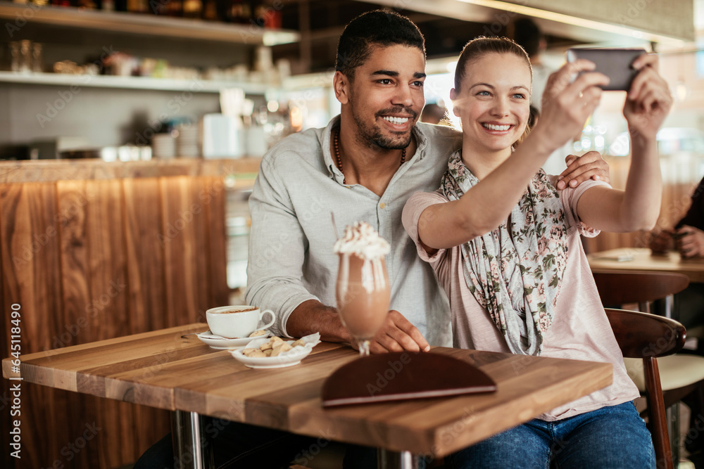 Young mixed couple taking a selfie in a cafe