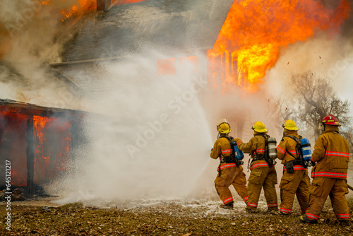 four firefighters advancing on a fire