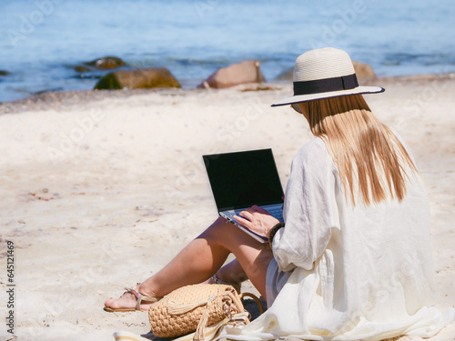 Obraz na płótnie young woman uses laptop computer on the beach. distance work, freelancer and blogger concept. WiFi unlimited w salonie
