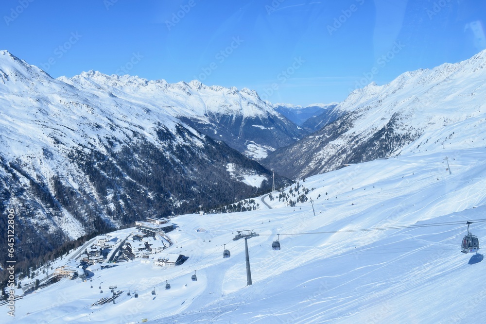 Gondola ski lifts in Hochgurgl ski resort, backdropped by the Otztal valley and the snow capped alpine mountains in Tyrol, Austria.