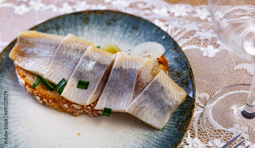 Fototapeta Naklejka Na Ścianę i Meble -  Delicious toast with marinated herring served with onions on dish in restaurant