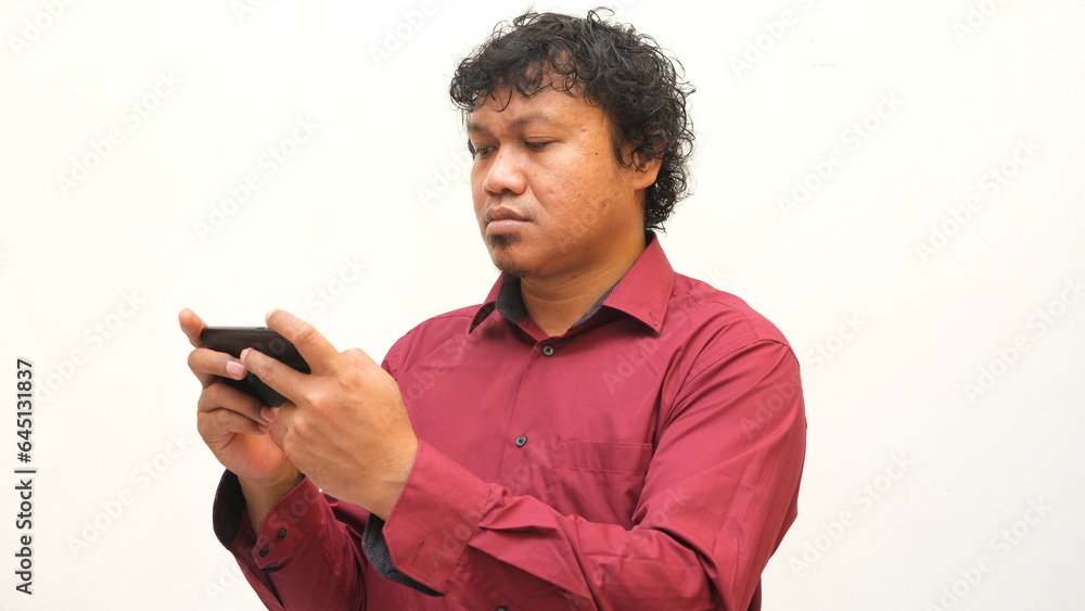 serious expression of asian man looking at mobile phone serious expression of asian man looking at mobile phone