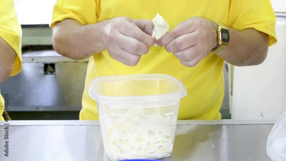 Joven desmenuzando queso blanco, comida callejera, cocinero preparando insumos, cocina en exterior.