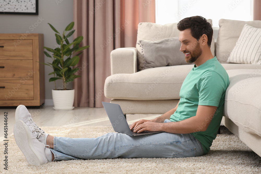 Man using laptop on floor near sofa at home Man using laptop on floor near sofa at home