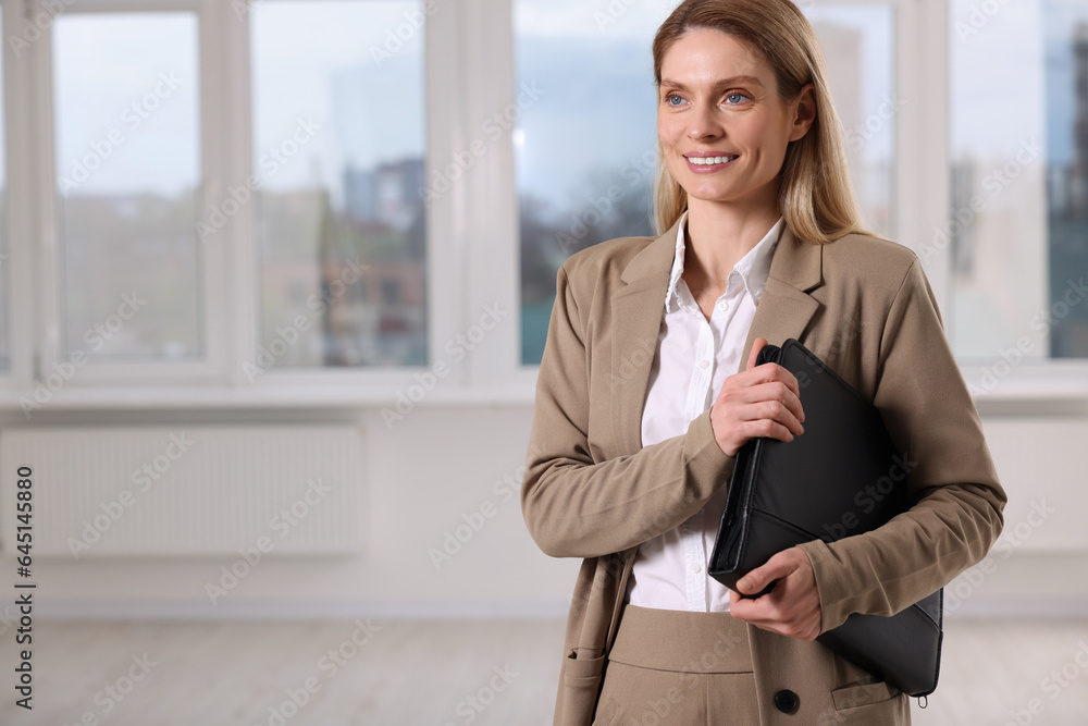 Happy real estate agent with leather portfolio indoors. Space for text Happy real estate agent with leather portfolio indoors. Space for text