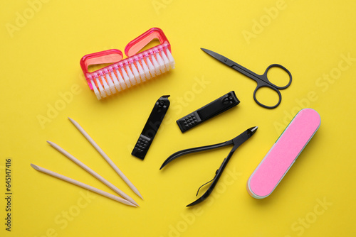 Set of pedicure tools on yellow background, flat lay