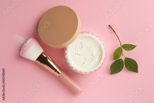 Rice loose face powder, makeup brush and branch on pink background, flat lay