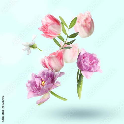 Beautiful flowers and green leaves falling on pastel turquoise background