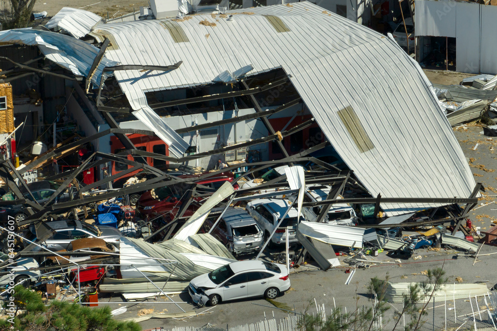 Naklejka premium Automotive workshop destroyed by hurricane wind with damaged cars under ruins in Florida. Consequence of natural disaster