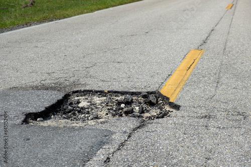 Dangerous pothole on american road surface. Ruined driveway in urgent need of repair photo