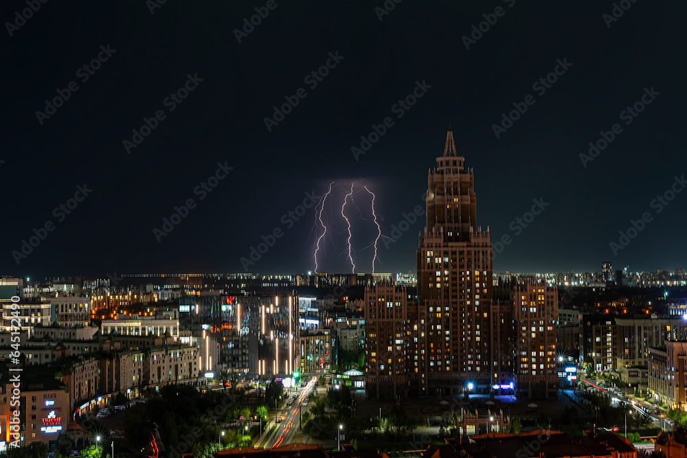 Astana, Kazakhstan, August, 2023. Night view of the skyscraper of the central street of the capital during a thunderstorm with lightning.