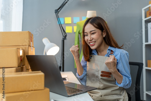 Small business startup, SME owner, female entrepreneur working on packaging parcel boxes, showing happy expression. business success Good feedback from customers independent business idea.