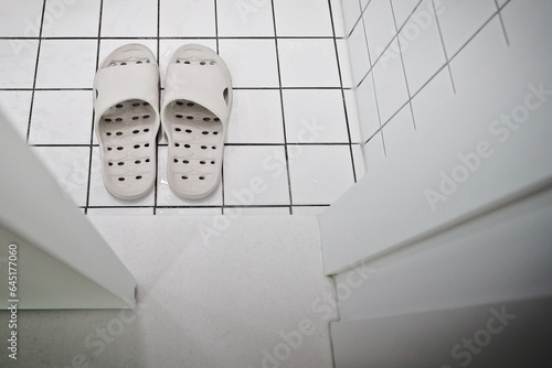 Bathroom shoes taken in front of the bathroom door that opens with a sliding door photo