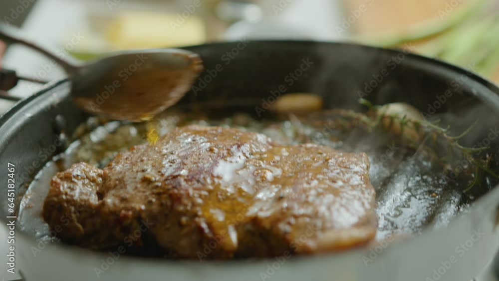 Chef using spoon for basting meat steak in a grill pan with butter while cooking delicious meat with garlic and aromatic rosemary sprig. Close-up shot Chef using spoon for basting meat steak in a grill pan with butter while cooking delicious meat with garlic and aromatic rosemary sprig. Close-up shot