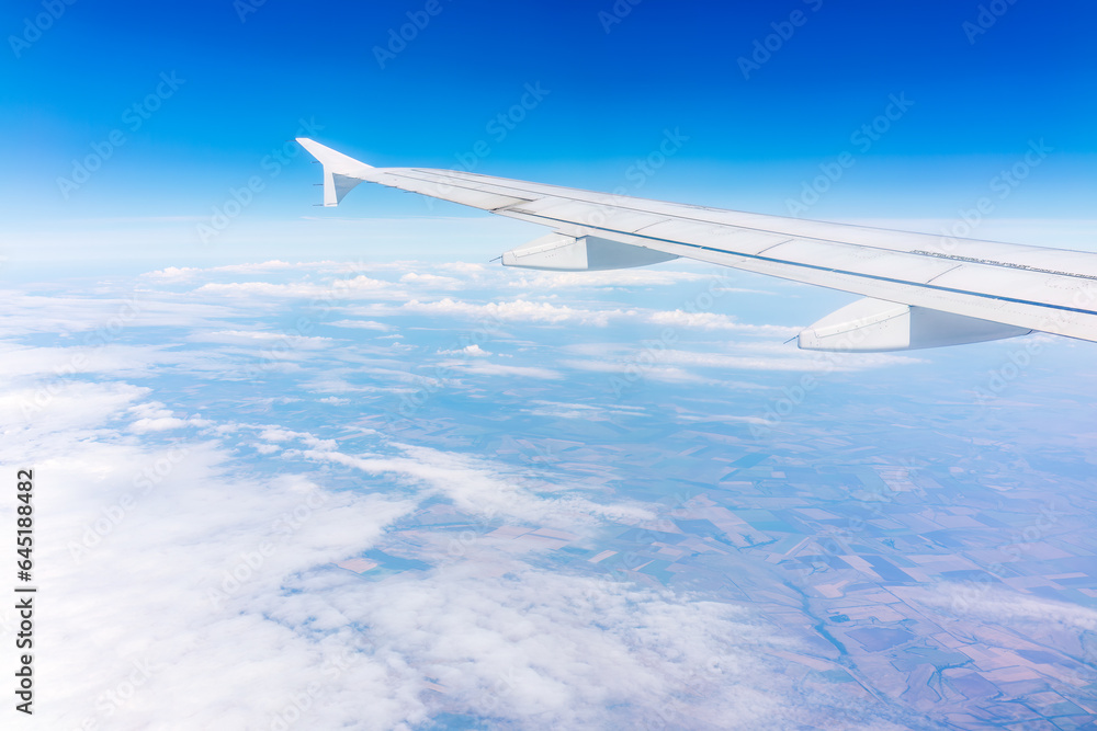 Fototapeta premium View from the airplane window at a beautiful cloudy sky and the airplane wing