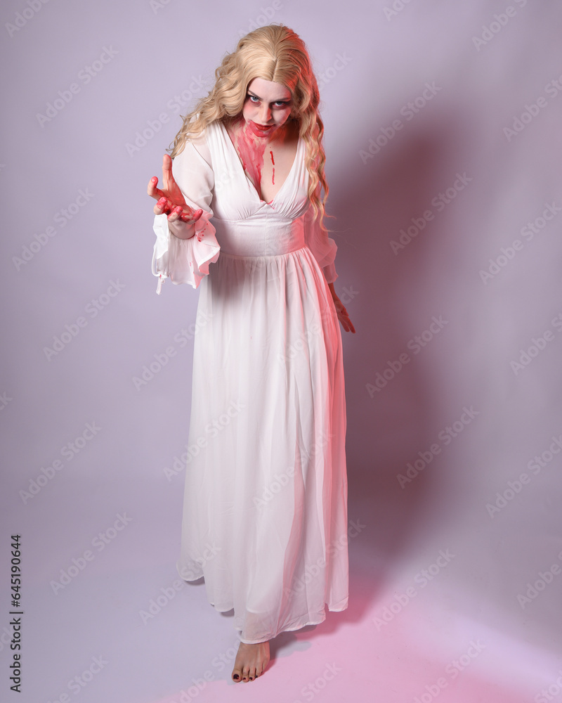 Full length portrait of scary vampire zombie bride, wearing elegant halloween fantasy costume dress with bloody red paint splatter. standing walking pose. Isolated on white studio background Full length portrait of scary vampire zombie bride, wearing elegant halloween fantasy costume dress with bloody red paint splatter. standing walking pose. Isolated on white studio background